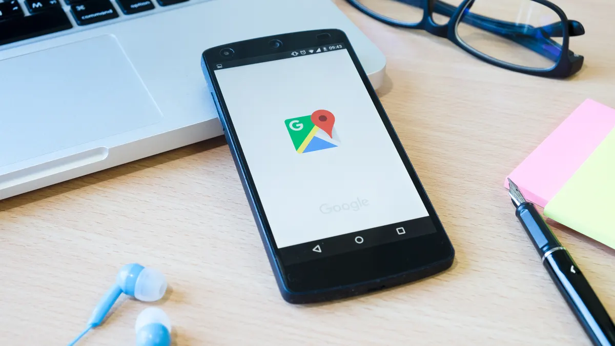Smartphone ouvert sur Google Maps posé sur un bureau