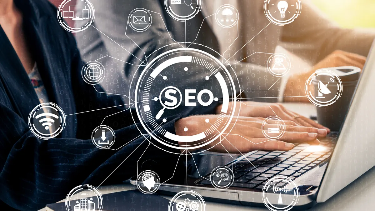 Mains sur un ordinateur portable entourées d’icônes de recherche et de SEO